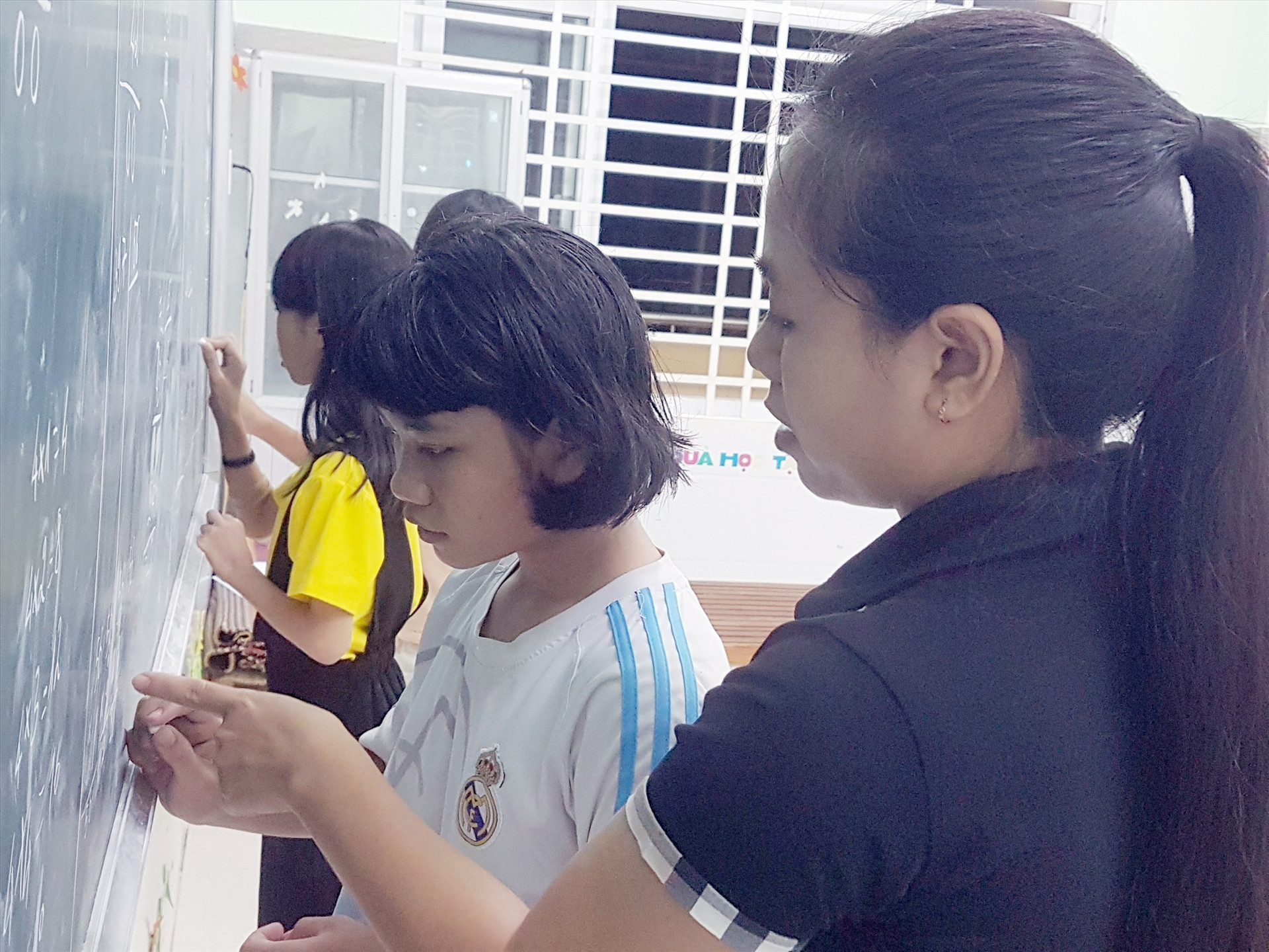 Cô Nguyễn Thị Thu Hiền kèm cho trẻ bậc tiểu học học thêm ban đêm tại Làng Hòa Bình. Ảnh: D.L
