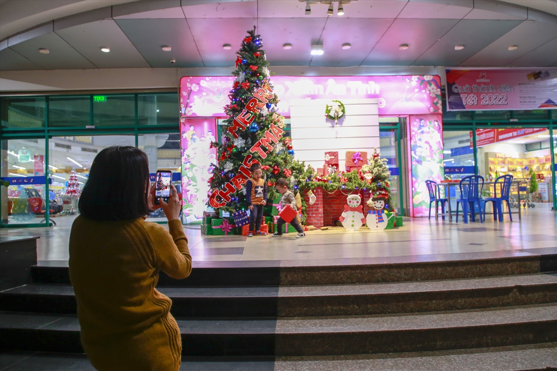 Mọi người chụp hình bên cây thông noel tại siêu thị. Ảnh: T.L