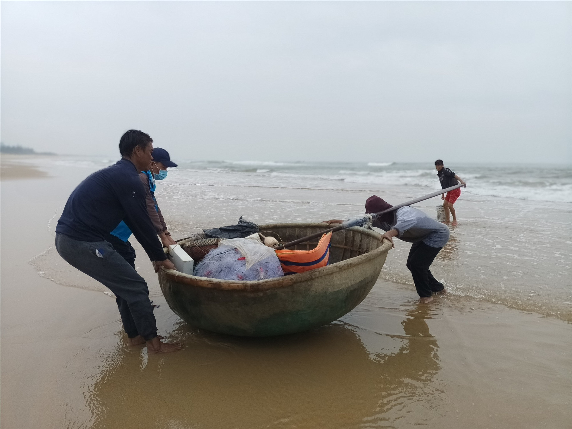 Ngư dân giúp nhau kéo thúng vào bờ để gỡ cá mắc lưới.