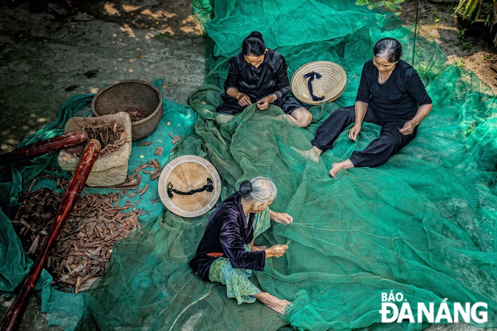 Phụ nữ trong làng với công việc vá trủ (lưới).