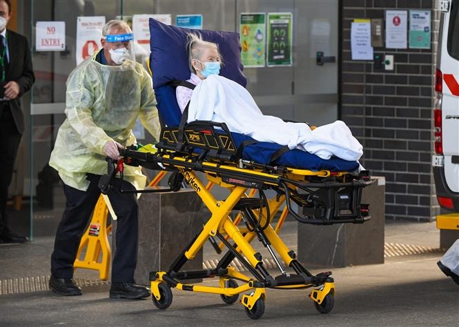 Nhân viên y tế chuyển bệnh nhân Covid-19 tới bệnh viện tại Melbourne, Australia. Ảnh: AFP/ TTXVN