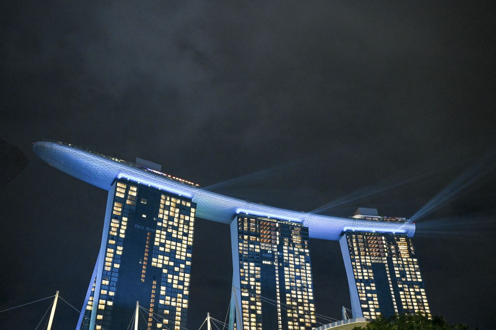 Đèn chùm chiếu sáng từ đỉnh khách sạn Marina Bay Sands ở Singapore trước thời khắc giao thừa tối 31-12-2021. Ảnh: AFP/TTXVN