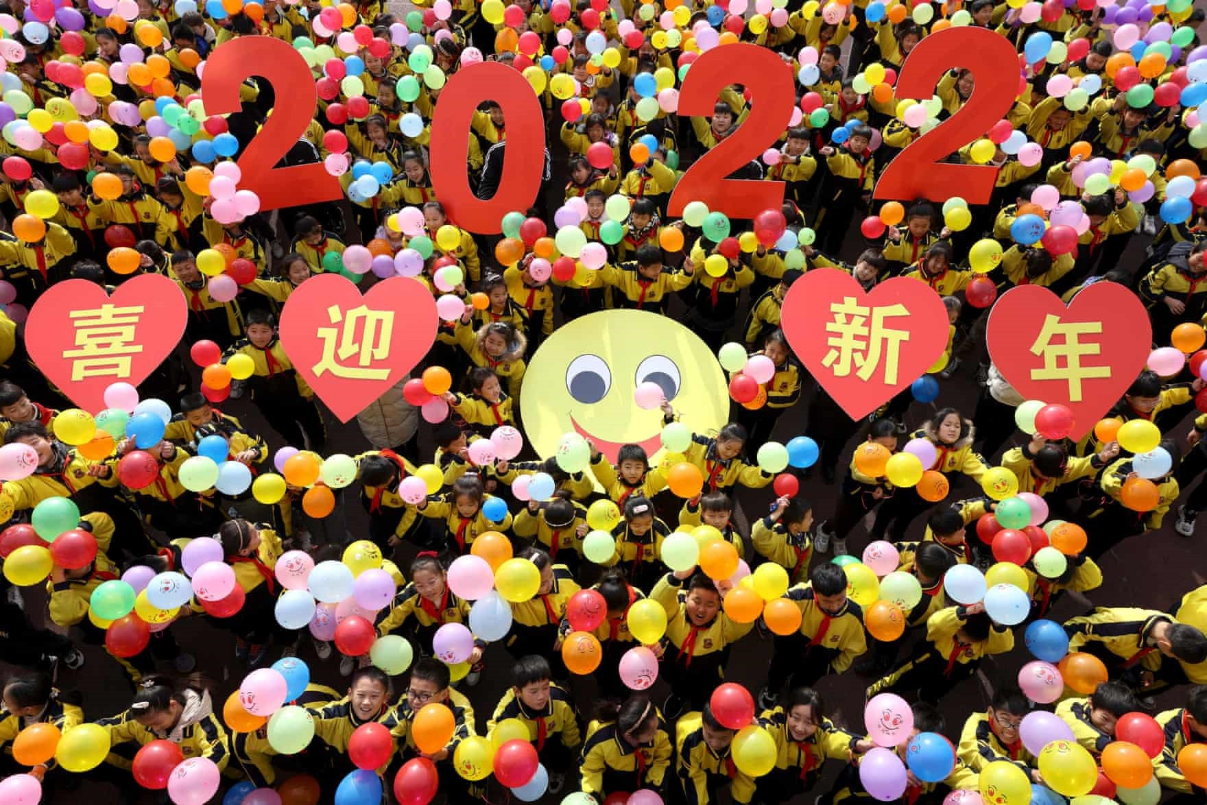 Zaozhuang, Trung Quốc Học sinh cầm biển báo 2022 và những chùm bóng bay nhiều màu sắc để chào đón năm mới.