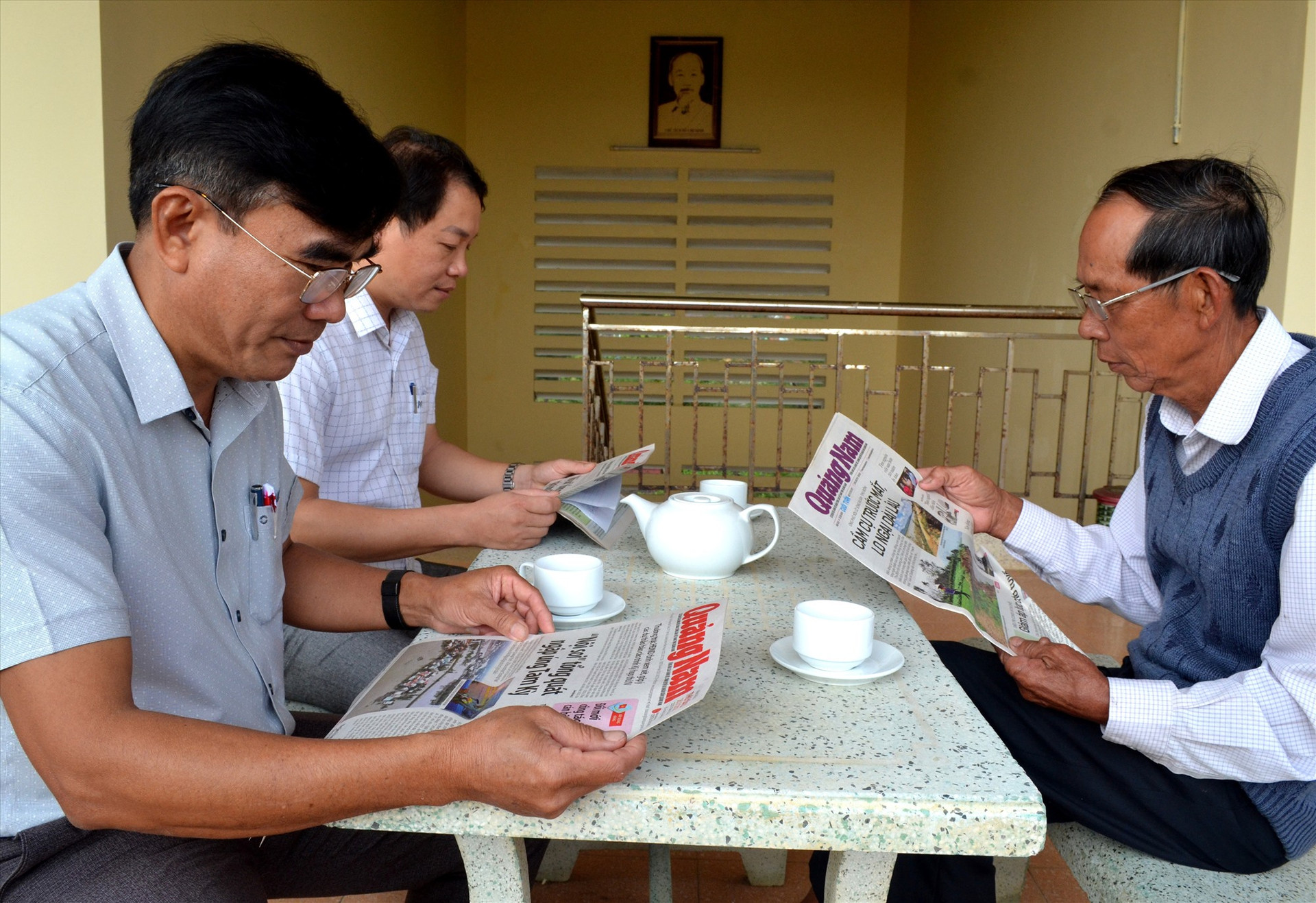 Cán bộ, đảng viên xã Bình Dương đọc báo và trao đổi công việc buổi sáng. Ảnh: VIỆT NGUYỄN