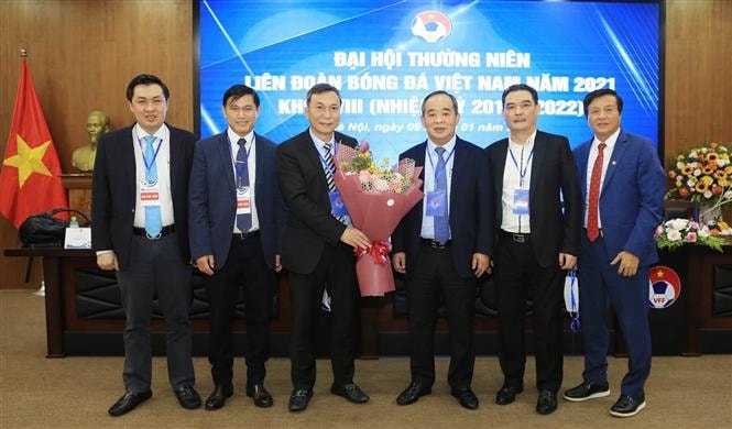 Quyền chủ tịch Liên đoàn Bóng đá Việt Nam Trần Quốc Tuấn nhận hoa chúc mừng từ Nguyên Chủ tịch Liên đoàn Bóng đá Việt Nam khóa VIII Lê Khánh Hải. Ảnh: TTXVN