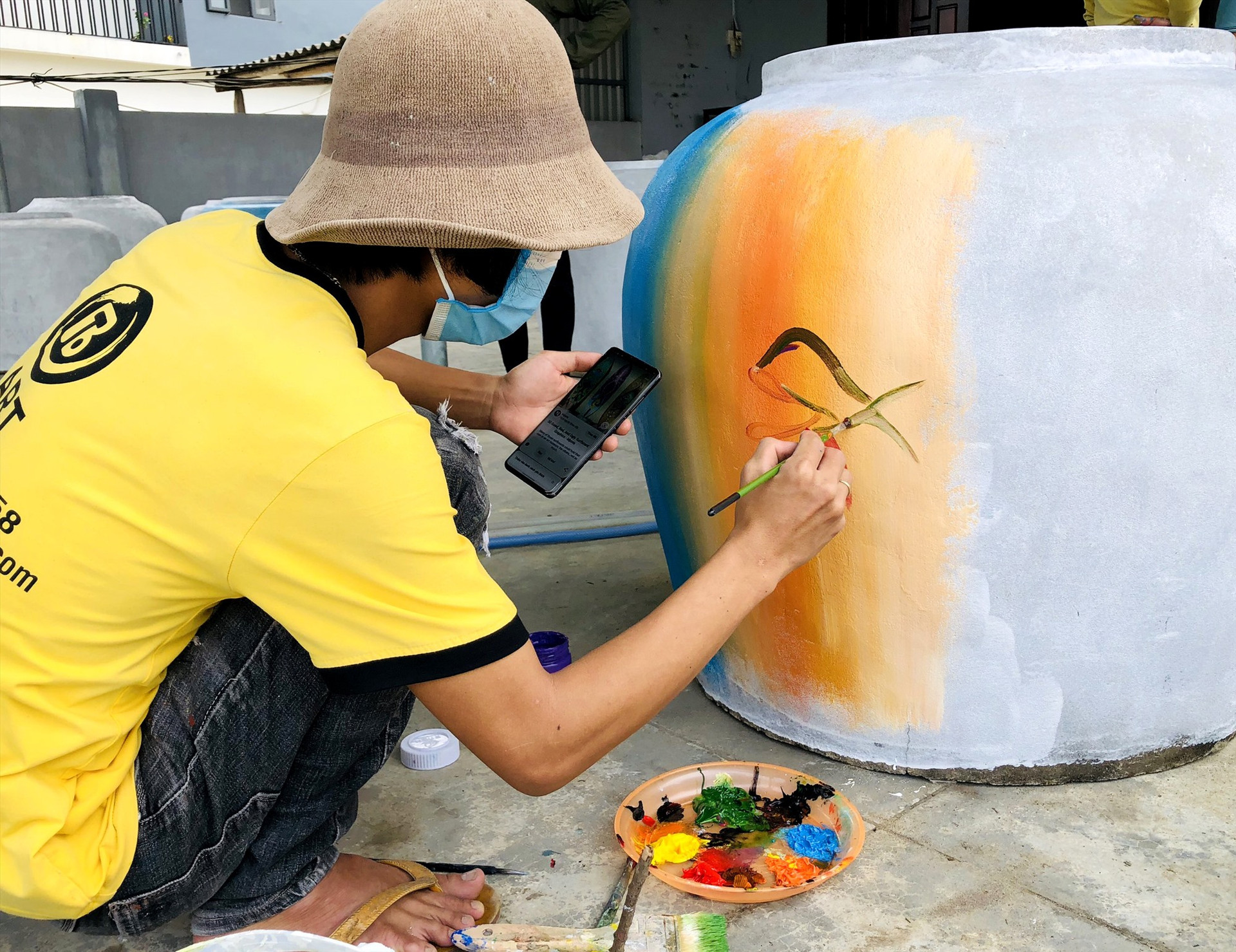 Người dân có kỹ năng hội họa trong thôn tham gia vẽ những bức tranh về đời sống, sinh hoạt ngư dân miền biển lên bề mặt chum. Ảnh: Q.S