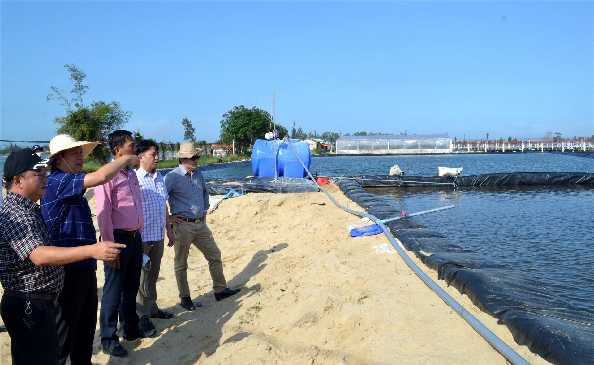 Ông Phạm Đình Chương (bìa trái) trình bày với Phó Chủ tịch UBND tỉnh Hồ Quang Bửu về xử lý nước sạch để nuôi tôm. Ảnh: VIỆT NGUYỄN