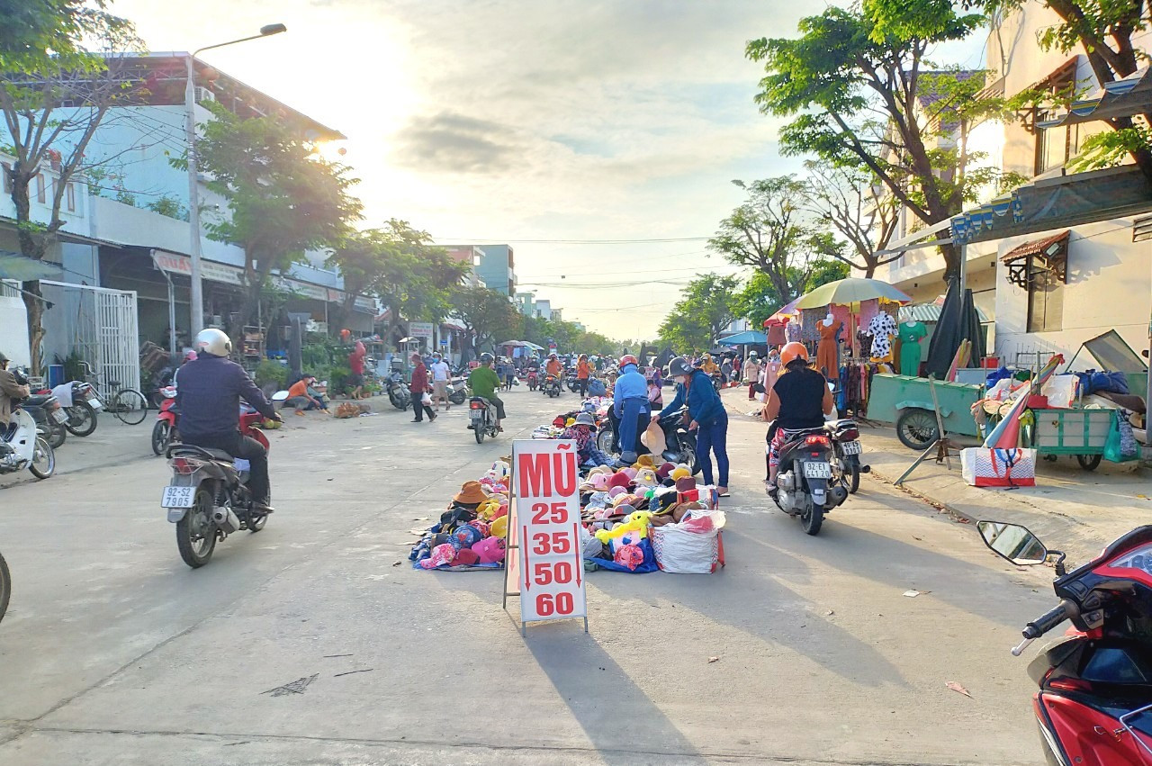Người dân chiếm dụng lòng đường Phạm Văn Đồng, gần chợ Ngã tư Ái Nghĩa để buôn bán. Ảnh: N.B