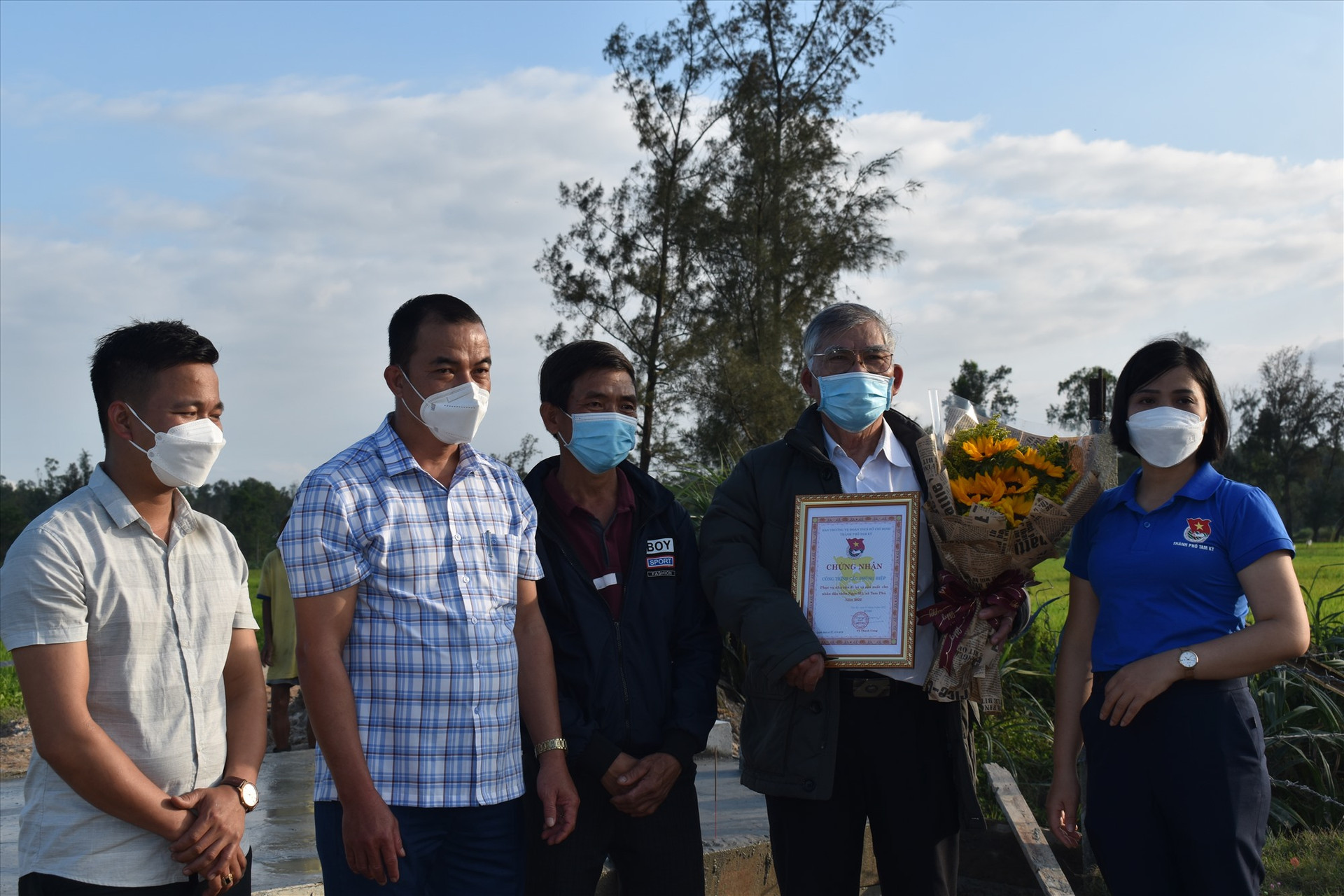 Chính quyền xã Tam Phú và Thành đoàn TP.Tam Kỳ tặng hoa cho ông Phùng tại lễ bàn giao cây cầu. Ảnh Q.T