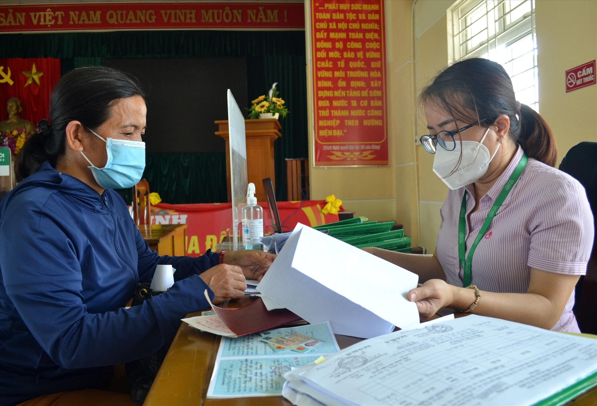 Bà Đỗ Thị Bích Hà giao dịch với cán bộ Phòng Giao dịch Ngân hàng CSXH Duy Xuyên. Ảnh: VIỆT NGUYỄN