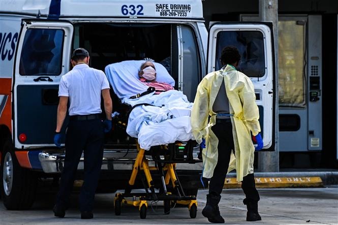 Nhân viên y tế chuyển bệnh nhân COVID-19 tới bệnh viện tại Coral Gables, Mỹ. Ảnh: AFP/ TTXVN