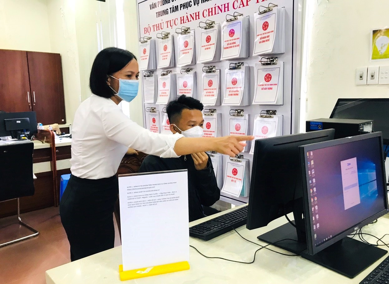 Nhân viên Bưu điện Quảng Nam hướng dẫn người dân đăng ký tài khoản, nộp hồ sơ trực tuyến khi đến làm thủ tục cấp lý lịch tư pháp. Ảnh: V.A