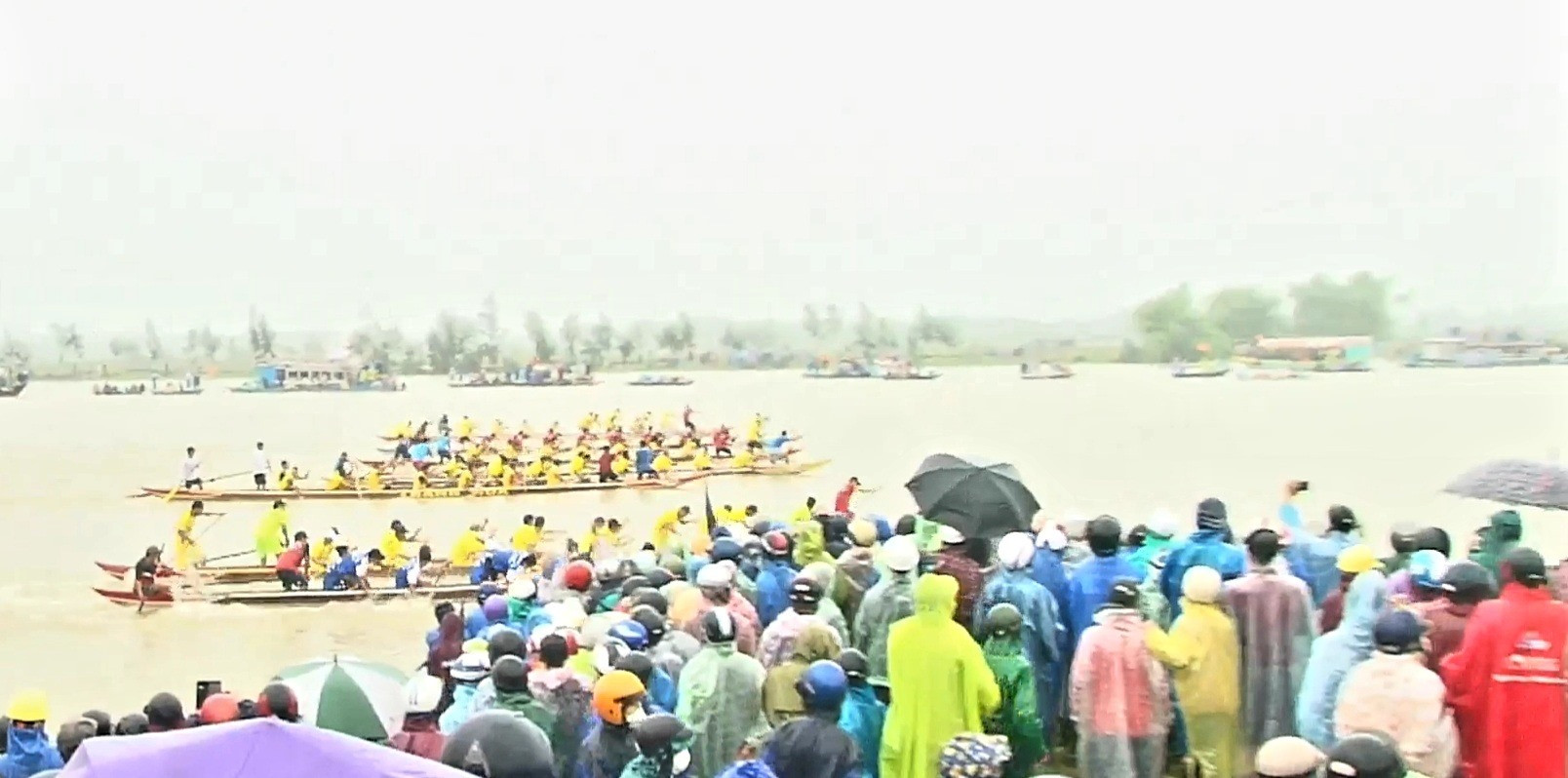Mặc dù trời mưa to kéo dài nhưng rất đông khán giả dự xem giải đua thuyền.  Ảnh: PV