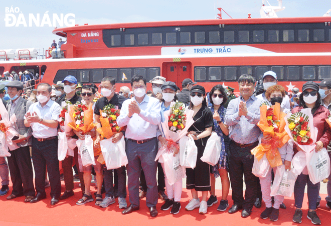 Lãnh đạo thành phố Đà Nẵng và tỉnh Quảng Ngãi tặng hoa chúc mừng 20 hành khách đầu tiên đặt chân lên đảo Lý Sơn từ tàu Trưng Trắc. Ảnh: THÀNH LÂN - VĂN HOÀNG