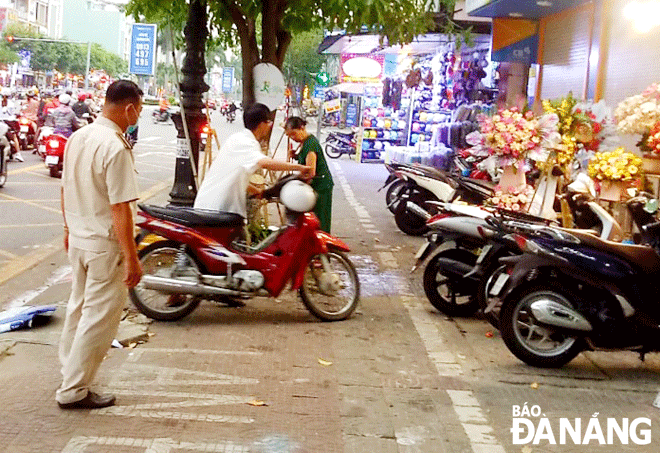 Lực lượng chức năng phường Thanh Khê Đông nhắc nhở một cơ sở kinh doanh trên địa bàn để xe đúng quy định, trả lại phần đường cho người đi bộ.  Ảnh: NGỌC HÀ