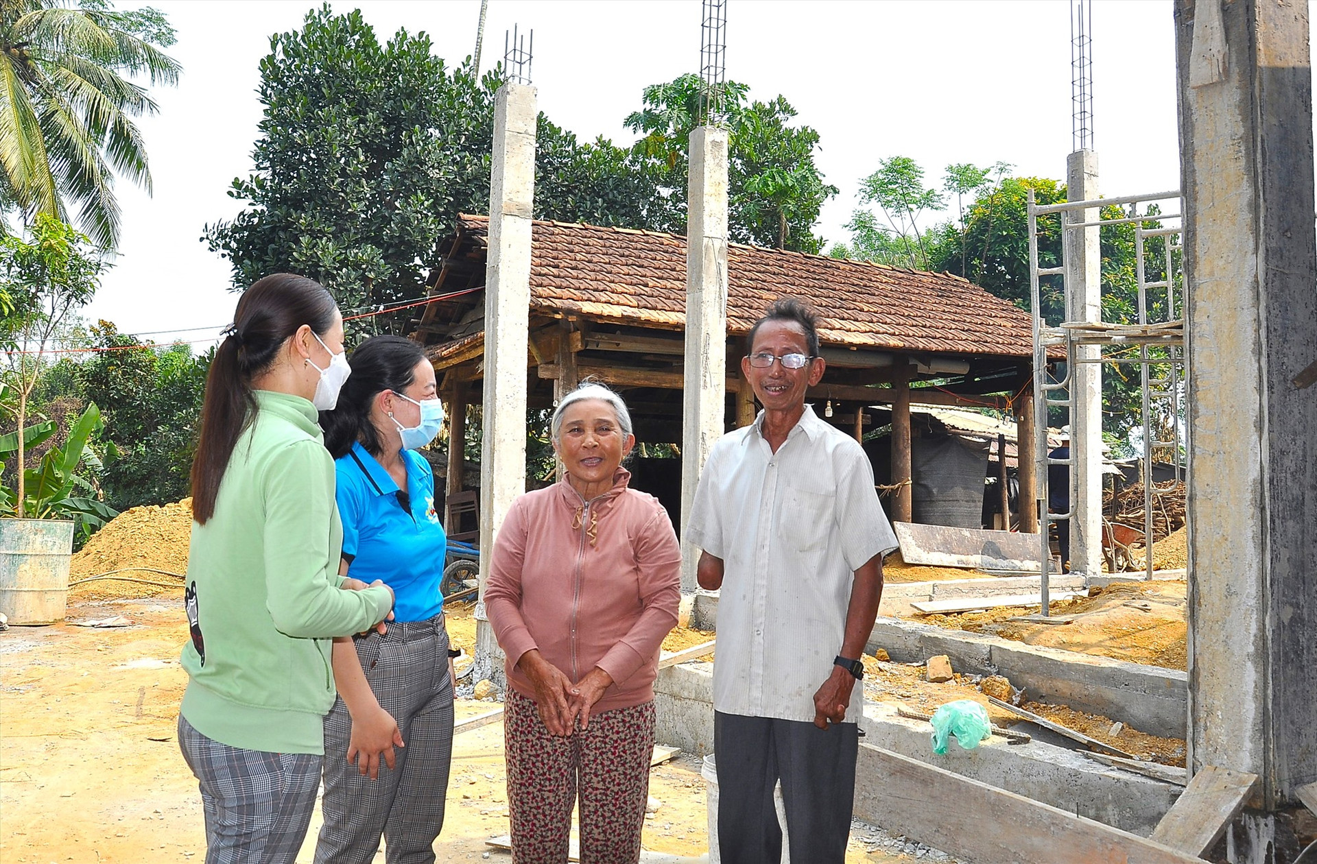 Vợ chồng bà Nguyễn Thị Chấn nói chuyện với cán bộ Hội LHPN xã Hiệp Thuận đến thăm. Phía sau là ngôi nhà mới của vợ chồng bà đang được xây dựng. Ảnh: P.V