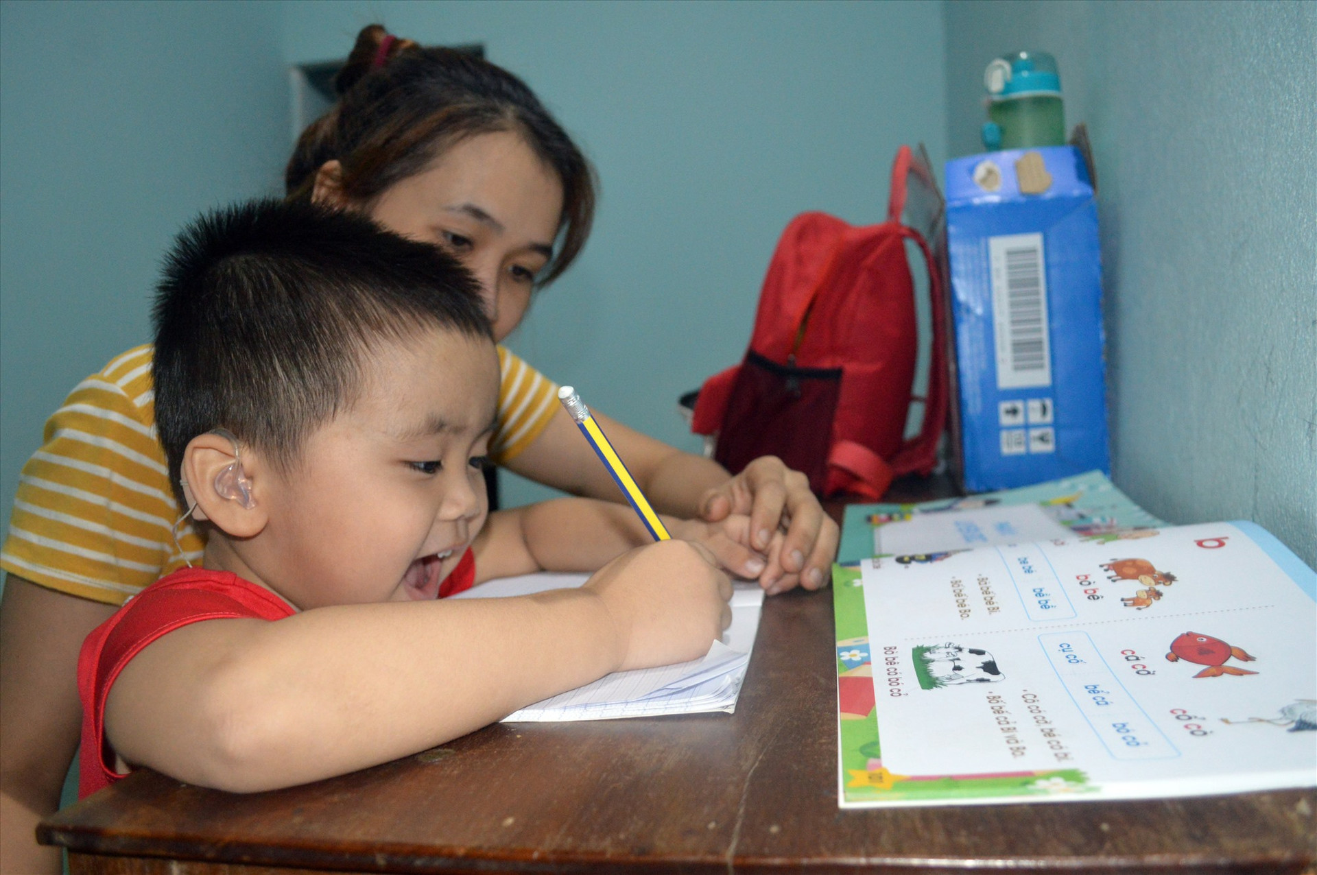 Mặc dù vẫn chưa thể nghe nói được, nhưng chị Trâm vẫn dạy Dương viết chữ vào mỗi buổi tối. ẢNH: THANH VIỆT