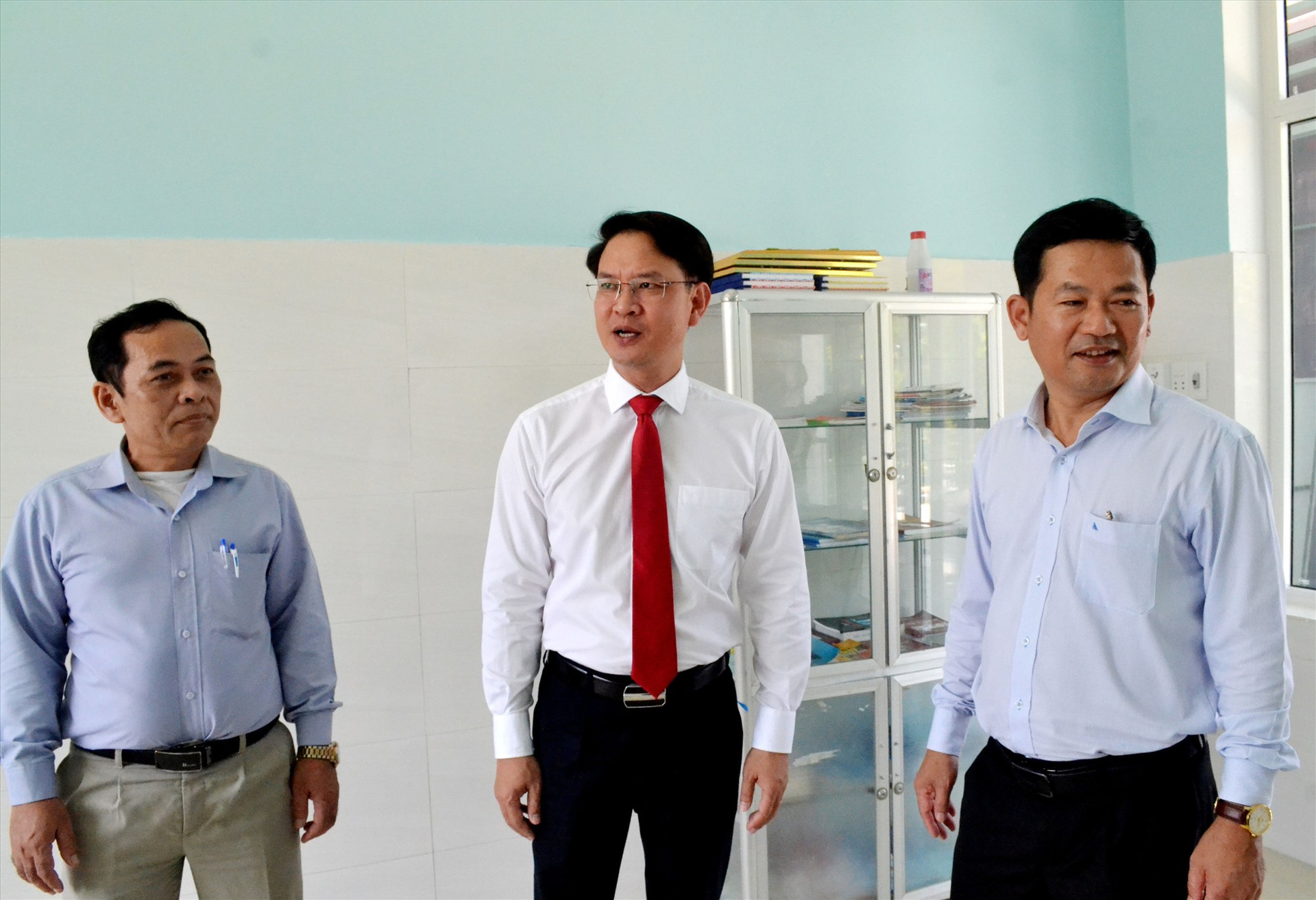 Ông Hà Thạch (giữa) trao đổi với lãnh đạo huyện Phước Sơn về sử dụng Trạm Y tế xã Phước Thành sau khi được bàn giao đưa vào hoạt động. Ảnh: VIỆT QUANG