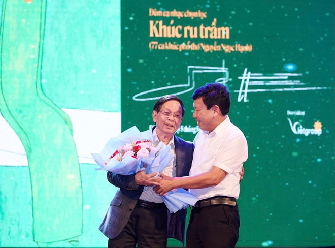 Ông Trần Úc, Chủ tịch UBND thị xã Điện Bàn, tỉnh Quảng Nam (phải) tặng hoa chúc mừng nhà thơ Nguyễn Ngọc Hạnh trong đêm nhạc Khúc ru trầm, ngày 5-5 vừa qua. (Ảnh do nhân vật cung cấp)
