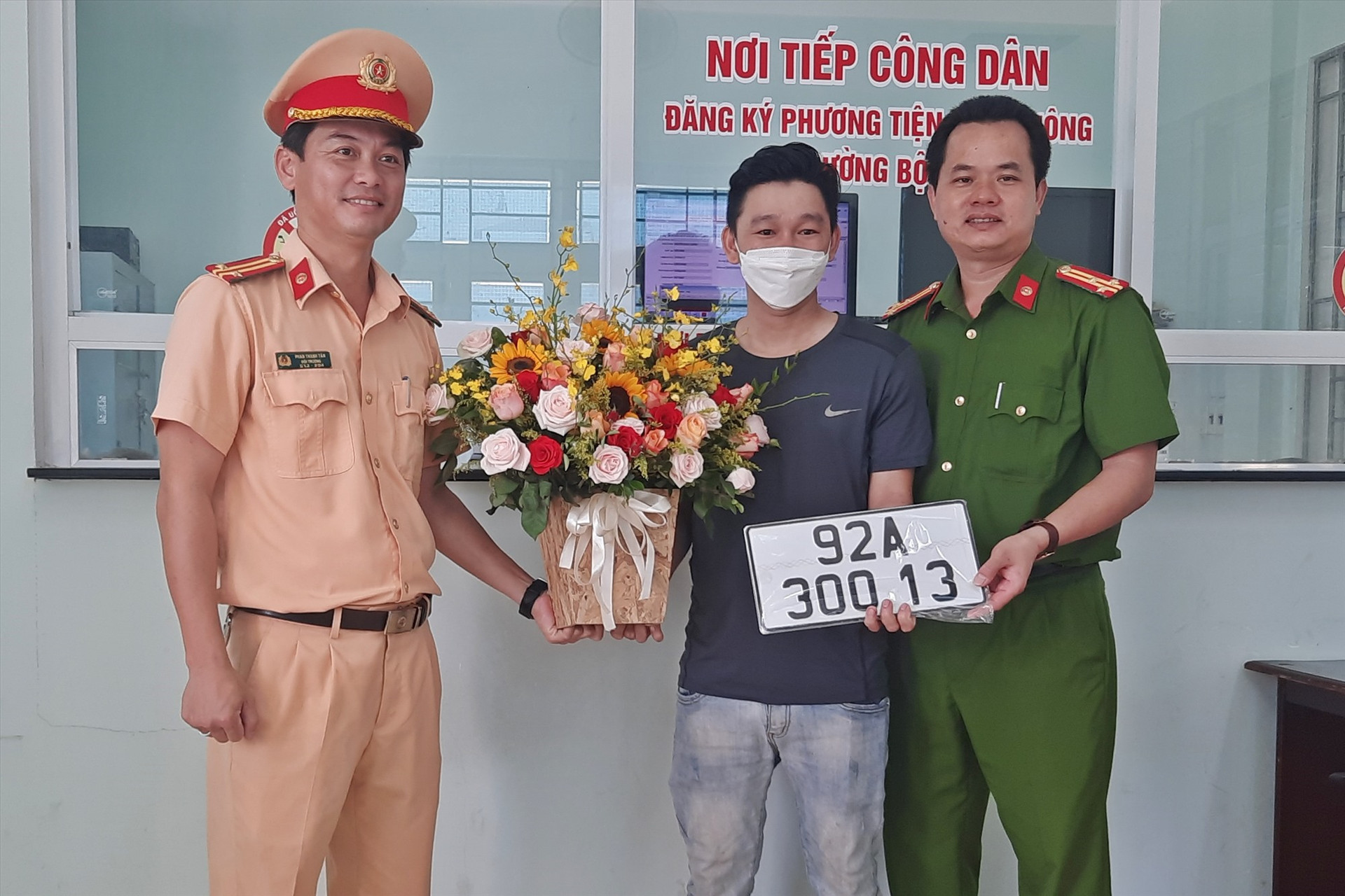 Công an huyện Núi Thành tặng hoa chúc mừng ông Nguyễn Ngọc Quảng - người đầu tiên thực hiện đăng ký mới xe ô tô theo Thông tư 15 ở địa phương này. Ảnh: Đ.C