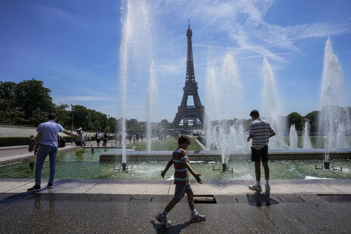 Nhiều người giải nóng tại các vòi nước cộng cộng gần tháp Effeil ở Paris, Pháp. Ảnh: AP