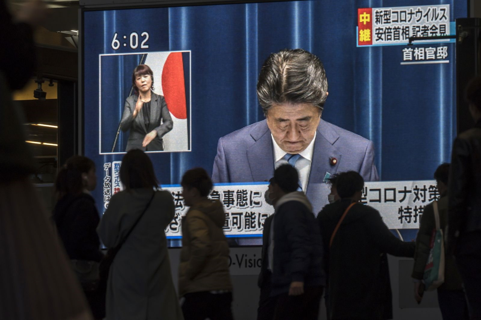 Người dân ở Osaka, Nhật Bản, đi ngang qua màn hình chiếu trực tiếp cảnh Abe nói về đại dịch Covid-19 vào năm 2020