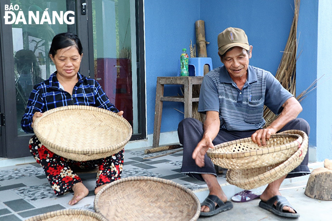 Bà Nguyễn Thị Hiên (bên trái) thỉnh thoảng đan vài cái rổ để đỡ nhớ nghề nhưng thu nhập chẳng bõ bèn gì. Ảnh: V.T.L