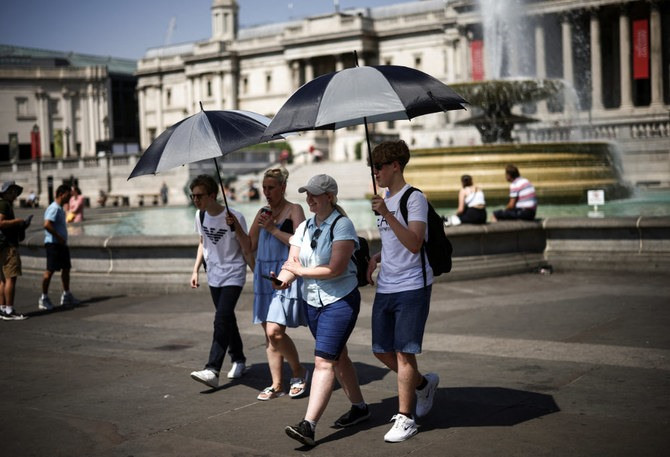 Người dân Anh sử dụng dù che nắng khi di chuyển dưới trời nóng tại quản trường Trafalgar, London ngày 19/7/2022. Ảnh: Reuters