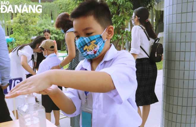 Học sinh được hướng dẫn sát khuẩn tay trước khi vào lớp. Ảnh: NGỌC HÀ.
