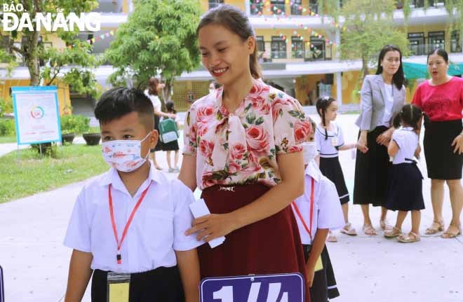 Giáo viên đón học sinh ngay cổng trường. Ảnh; NGỌC HÀ