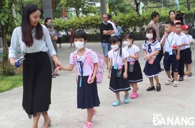 Dẫn các em vào lớp học. Ảnh: NGỌC HÀ