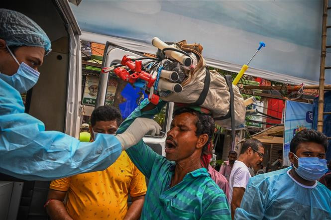 Nhân viên y tế lấy mẫu xét nghiệm COVID-19 cho người dân tại Kolkata, Ấn Độ. Ảnh: AFP/TTXVN