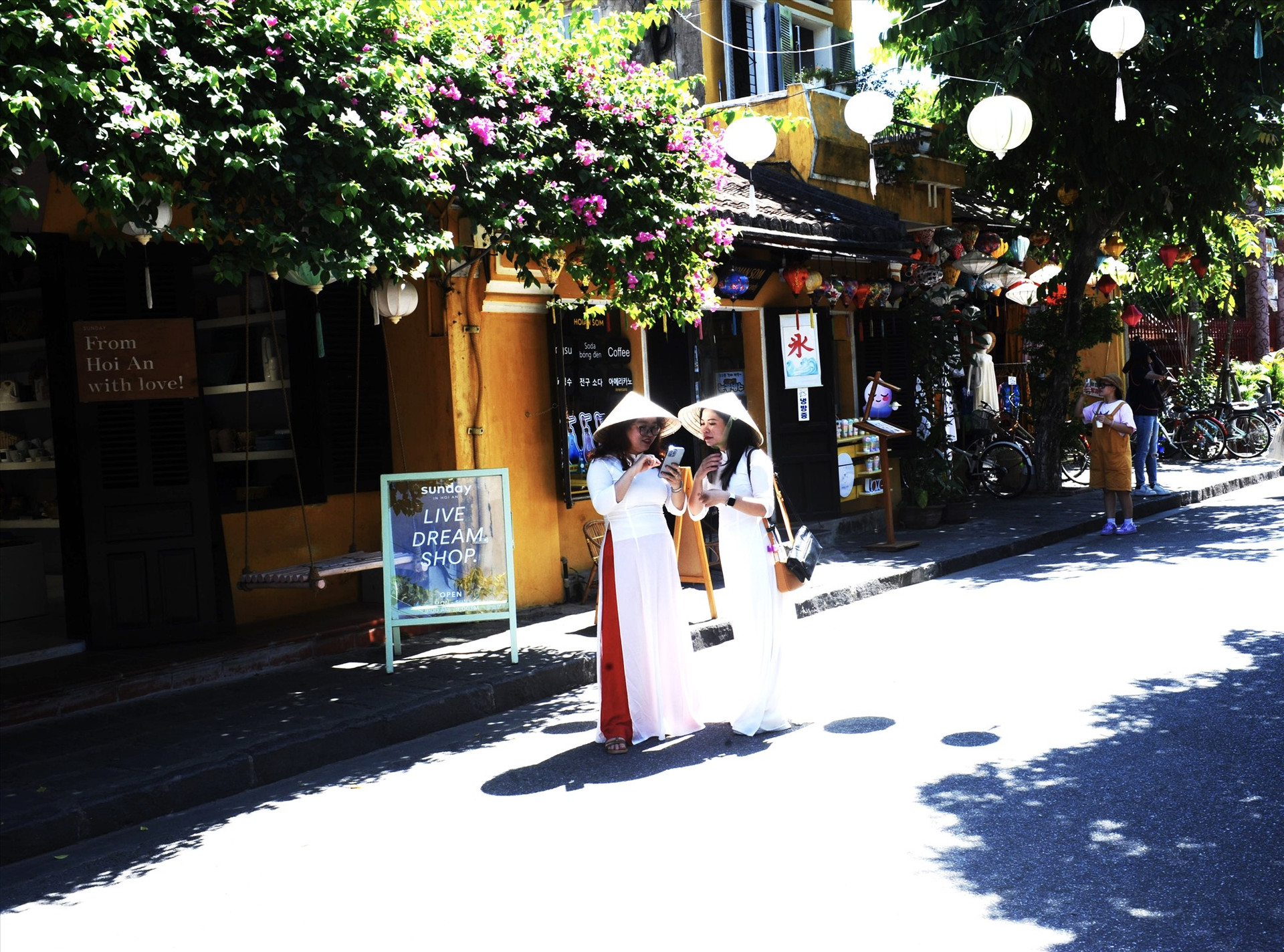 Du khách quốc tế xúng xính trong áo dài truyền thống trên đường phố Hội An những ngày diễn ra sự kiện. Ảnh: T.H