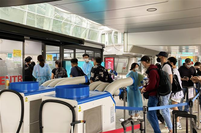 Các nhân viên y tế hướng dẫn khách nước ngoài về thủ tục xét nghiệm PCR tại điểm xét nghiệm ở sân bay Quốc tế Incheon. Ảnh: TTXVN