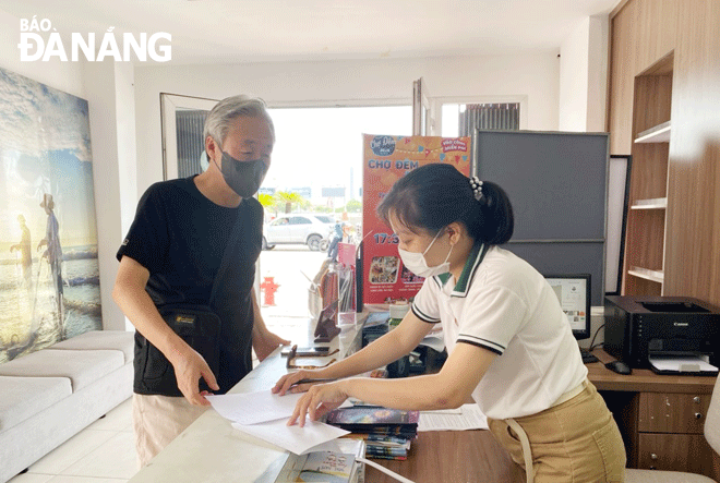 Chị Lê Thị Ái Chung (bên phải), chuyên viên Trung tâm Hỗ trợ du khách đang tư vấn, thông tin cho một vị khách tại văn phòng 108 Bạch Đằng. Ảnh: THU HÀ