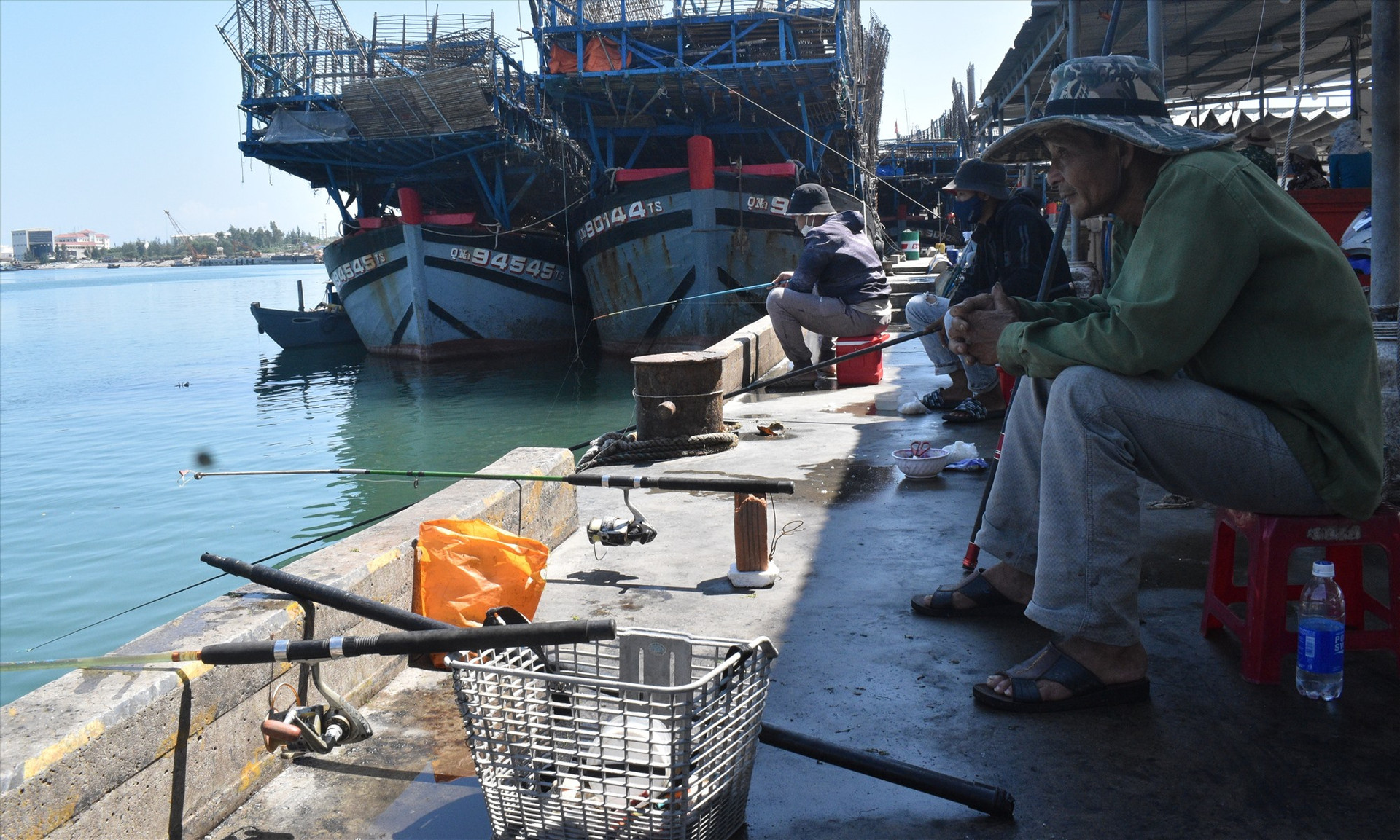 Hơn chục cần thủ ngồi san sát nhau ở cảng cá Tam Quang để câu cá dìa. Ảnh: N.Q