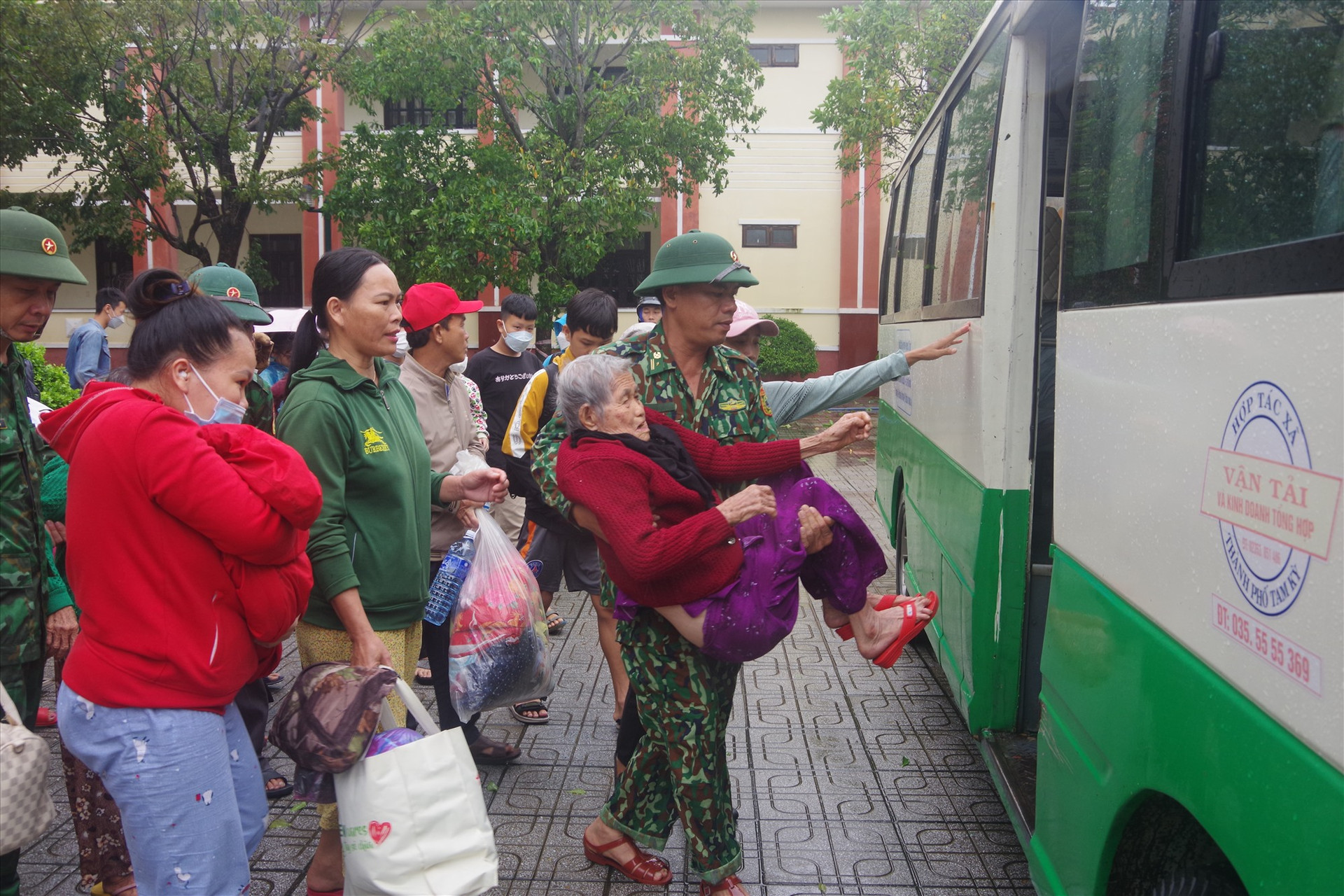 Cán bộ, chiến sĩ  Biên phòng Quảng Nam hỗ trợ người già yếu lên xe trở về với gia đình. Ảnh: HUỲNH CHÍN