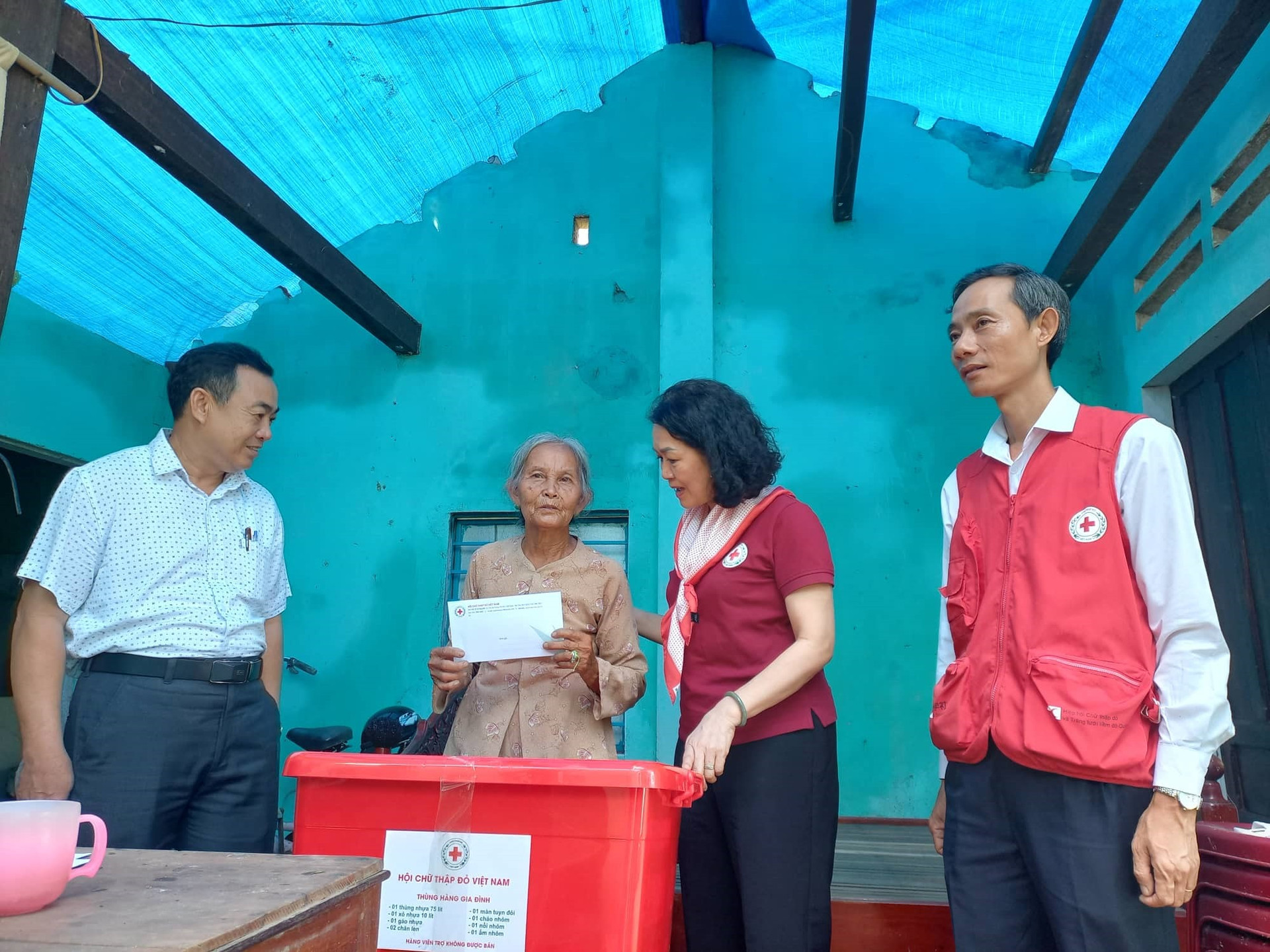 Hộ Chữ thập đỏ Việt Nam hỗ trợ thùng hàng gia đình và 5 triệu đồng cho bà Thái Thị Kim Anh ở xã Quế Phong (Quế Sơn) có nahf ở bị tốc mái hoàn toàn. ảnh DT