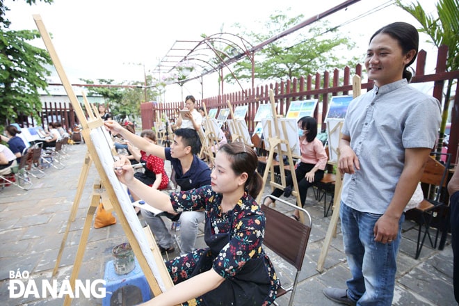 Họa sĩ Huỳnh Công Thành (bên phải) hướng dẫn các bạn trẻ tham gia chương trình trải nghiệm vẽ tranh tại xưởng. Ảnh: Đ.H.L