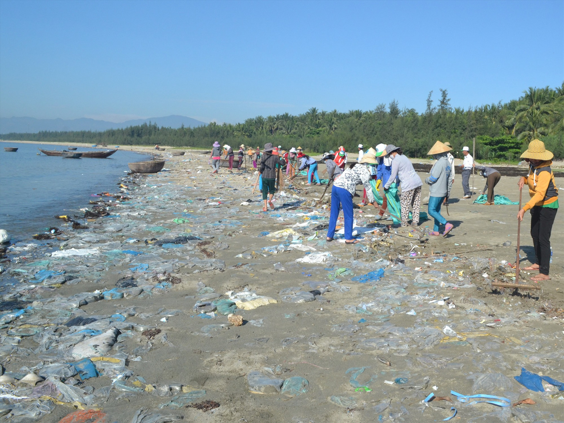 Người dân tham gia dọn rác thải ở bãi biển. Ảnh: NGUYỄN QUANG