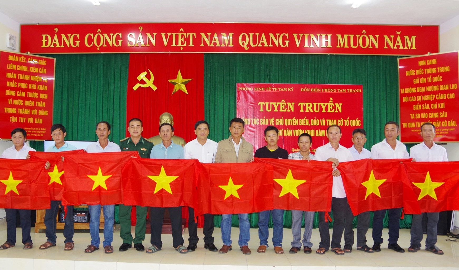 Đại diện Đồn Biên phòng Tam Thanh và Phòng Kinh tế thành phố Tam Kỳ trao tặng cờ Tổ quốc cho bà con ngư dân. Ảnh: VĂN VINH