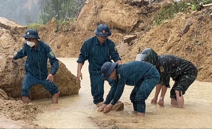 Lực lượng quân sự huyện Nông Sơn nỗ lực khơi thông điểm sạt lở tạo điều kiện cho dân đi bộ qua lại. Ảnh: N.P