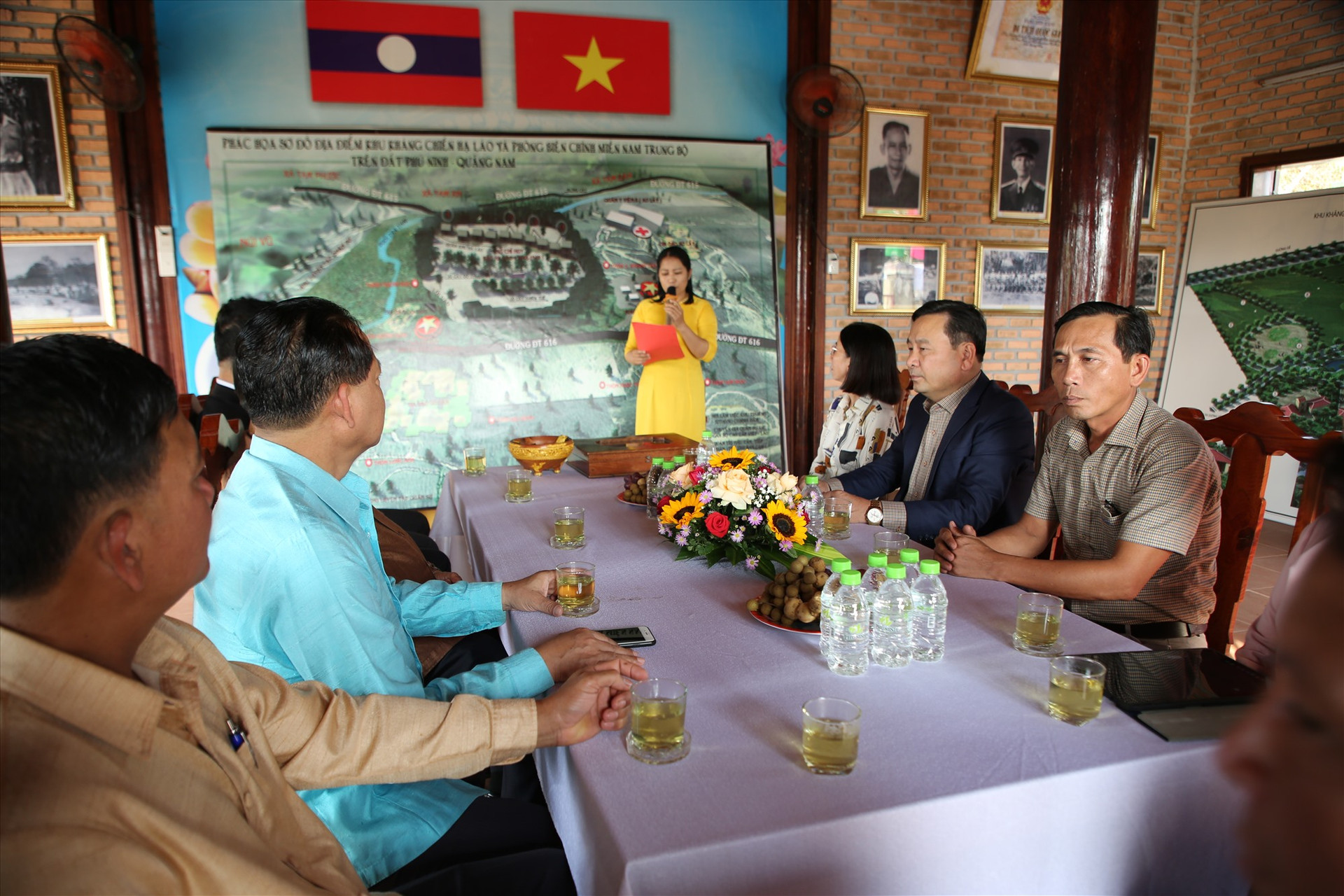 Các đại biểu lãnh đạo 2 tỉnh Quảng Nam - Sê Kông nghe thuyết minh về lịch sử kháng chiến Hạ Lào và quá trình hình thành Khu kháng chiến Hạ Lào tại Phú Ninh. Ảnh: Đ.N