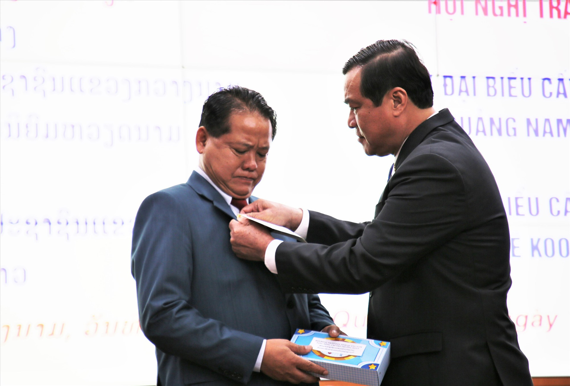 Phan Viet Cuong helps a delegate from Sekong province wear the Quang Nam- Sekong friendship logo.