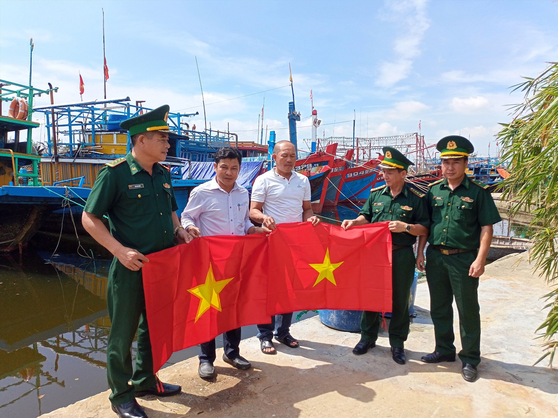 Tặng cờ tổ quốc cho ngư dân tại âu thuyền Tam Tiến. Ảnh: VĂN PHIN