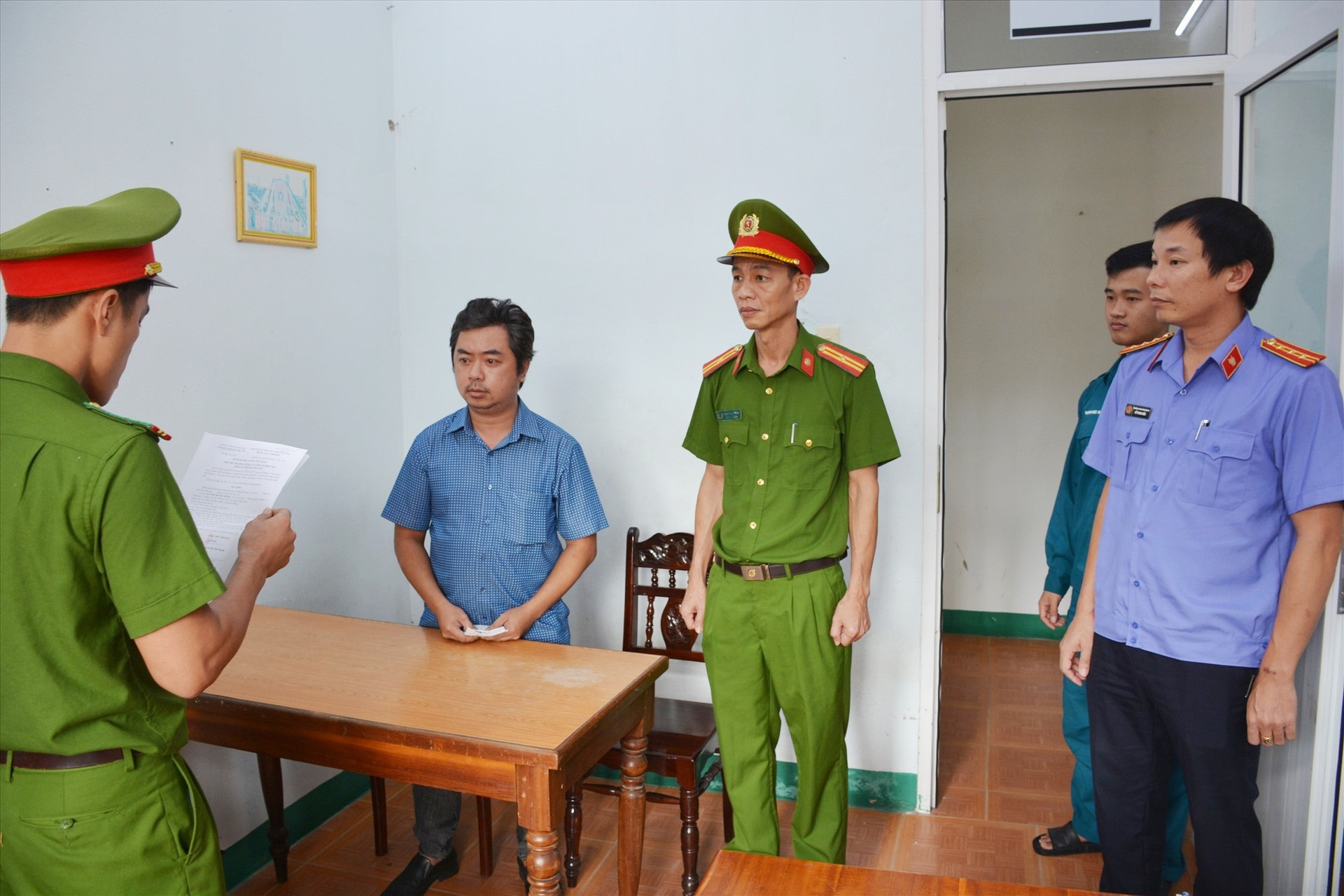 Công an tống đạt quyết định khởi tố bị can và lệnh bắt bị can để tạm giam đối với Nguyễn Hoàng Minh. Ảnh: M.T