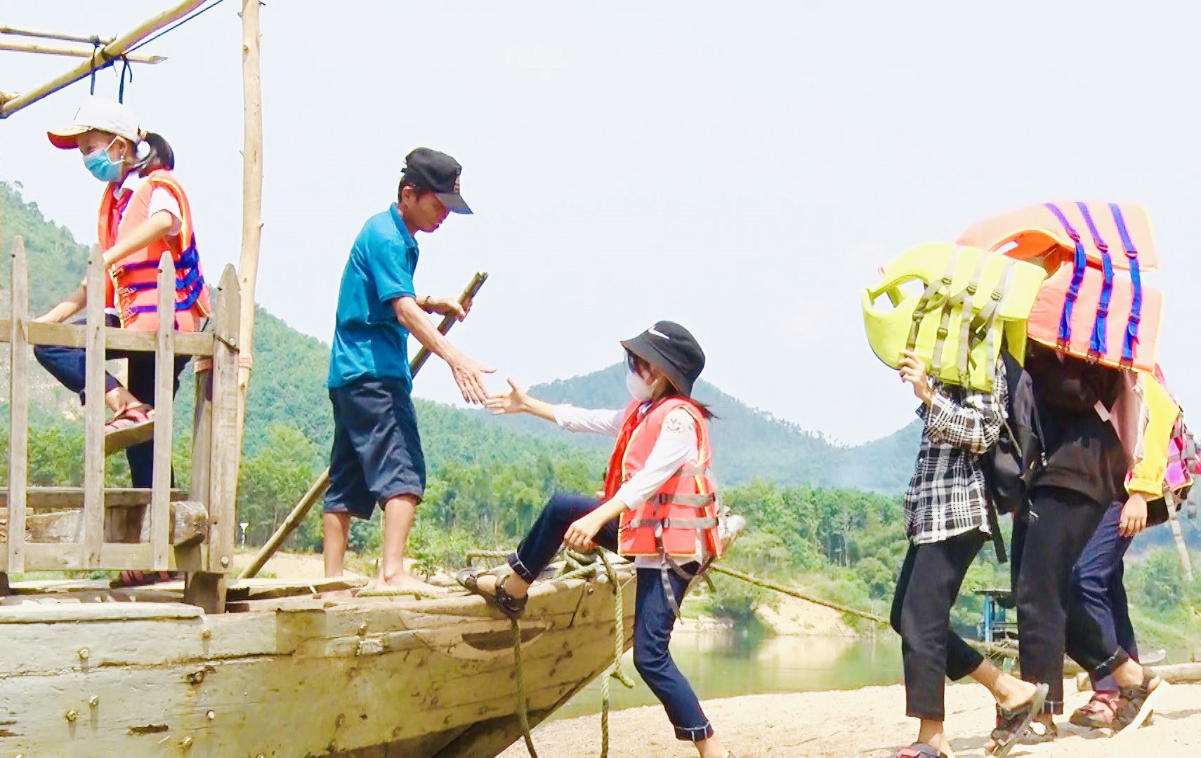Ông Phạm Văn Tiến đưa đón các em học sinh qua sông đến trường. Ảnh MINH THÔNG