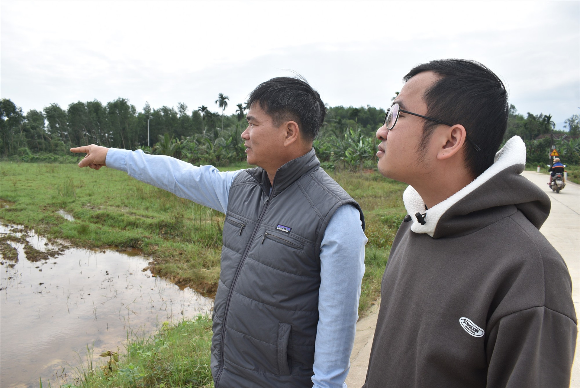 Ông Hà Trung Phong (bên trái) đang nói về khu đất bỏ hoang được ông vận động nhân dân để sản xuất lúa nước. Ảnh: Q.H.H