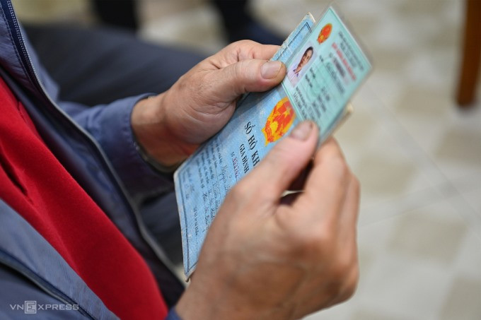 Một người dân cầm chứng minh thư và hộ khẩu giấy đi làm thẻ căn cước công dân gắn chip, ngày 9/3/2021.