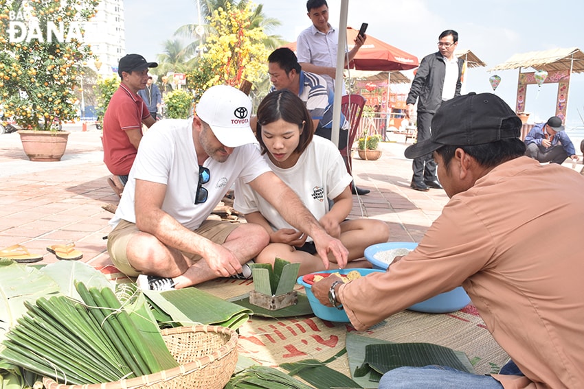 Anh Martin Czabel, quốc tịch Úc đang đi du lịch tại Đà Nẵng trải nghiệm hoạt động gói bánh chưng, bánh tét. Ảnh:THU HÀ
